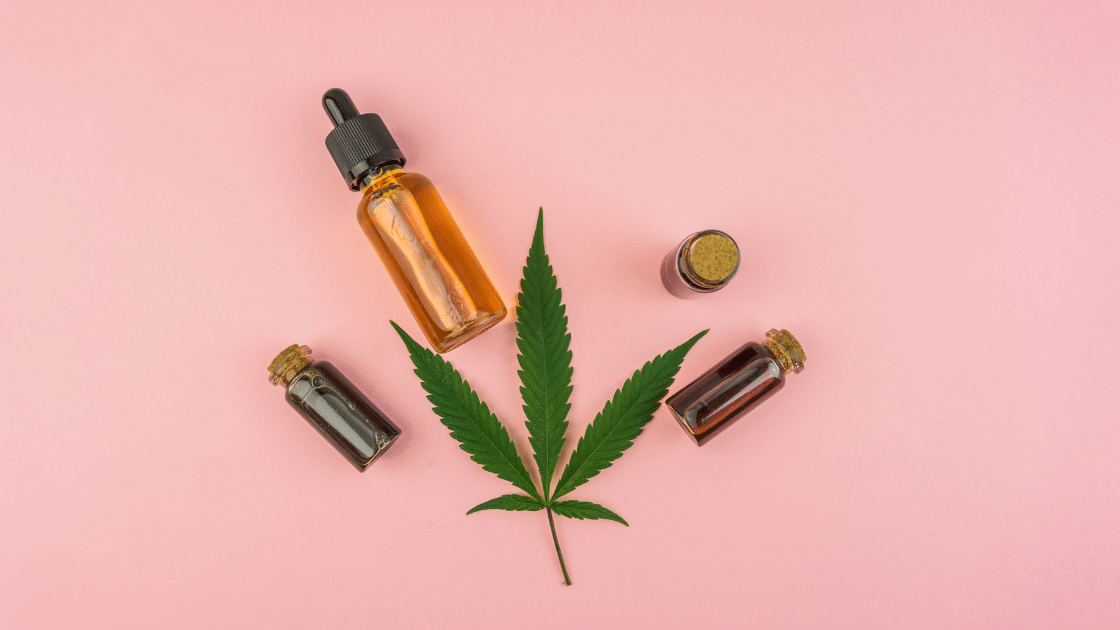 Hemp leaf featured with a cbd tincture bottle and small cork capped vials on a beautiful pick background