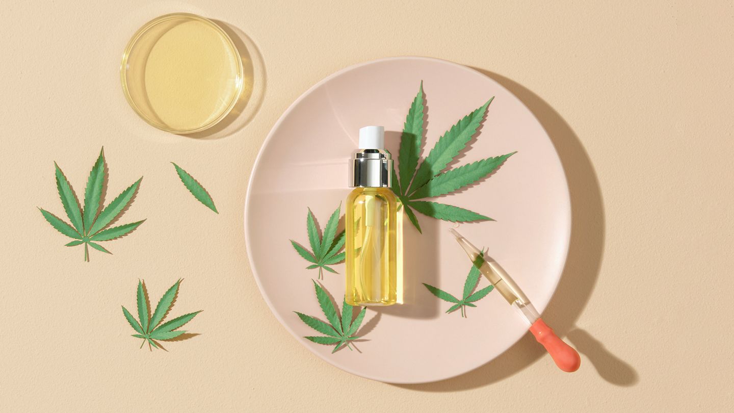 Hemp leaves around a dish containing a bottle of oil and a dropper