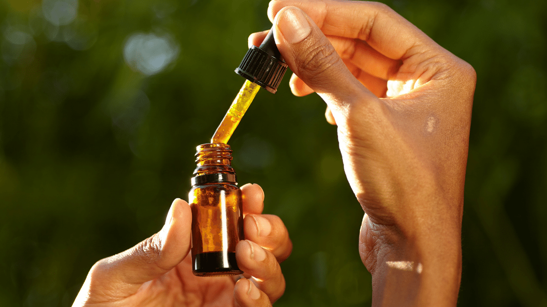 Woman's hands pulling a dropper full of CBD